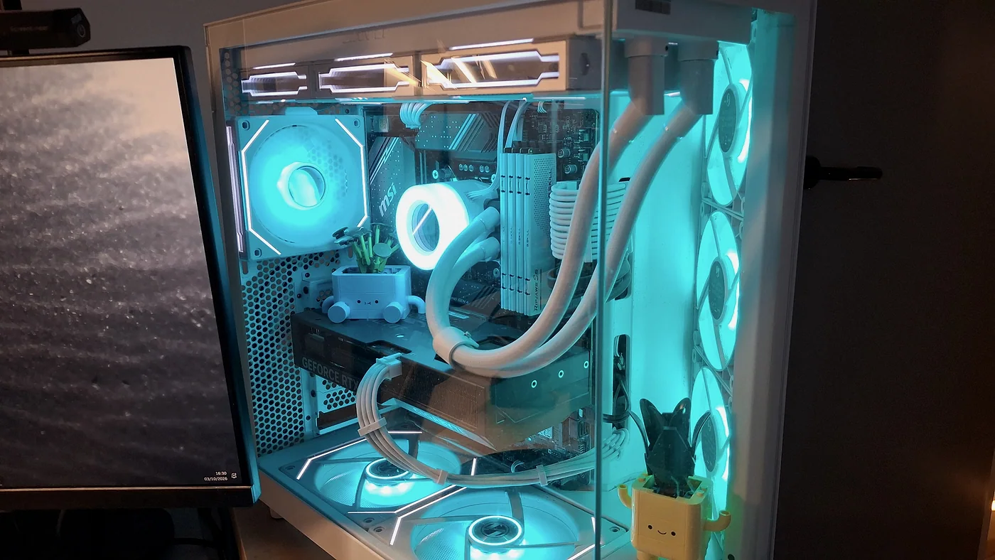 Gros plan sur l'intérieur du PC : carte graphique, refroidissement liquide blanc et ventilateurs bleu clair, avec de petites plantes en pot.